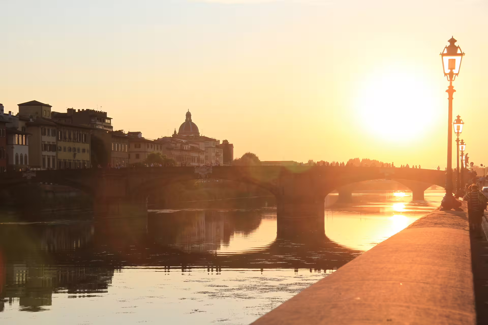 Golden sunset over the Arno River and historic bridge in Florence, Italy, seen on a private transfer from Rome to Florence