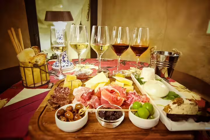 Elegant Rome food and wine pairing board with prosciutto, cheeses, olives and multiple glasses of Italian wines in a candlelit setting