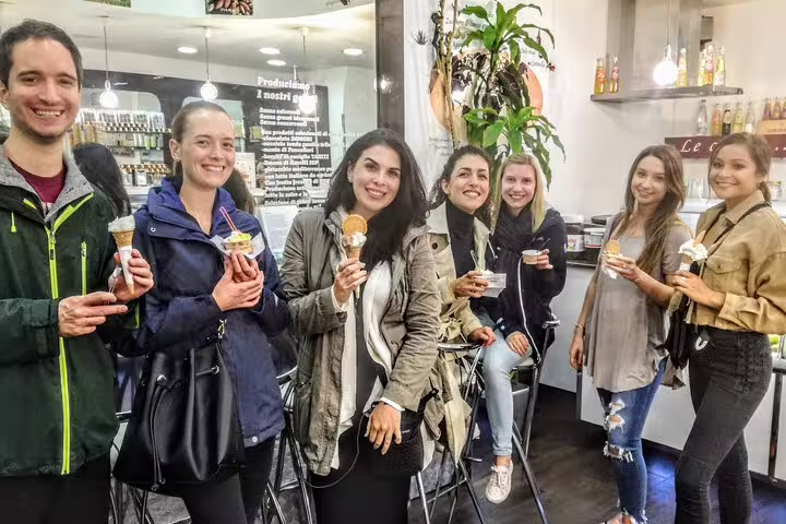 Happy group of travelers savoring fresh gelato cones inside a Rome gelateria on a Campo de Fiori street food tour.