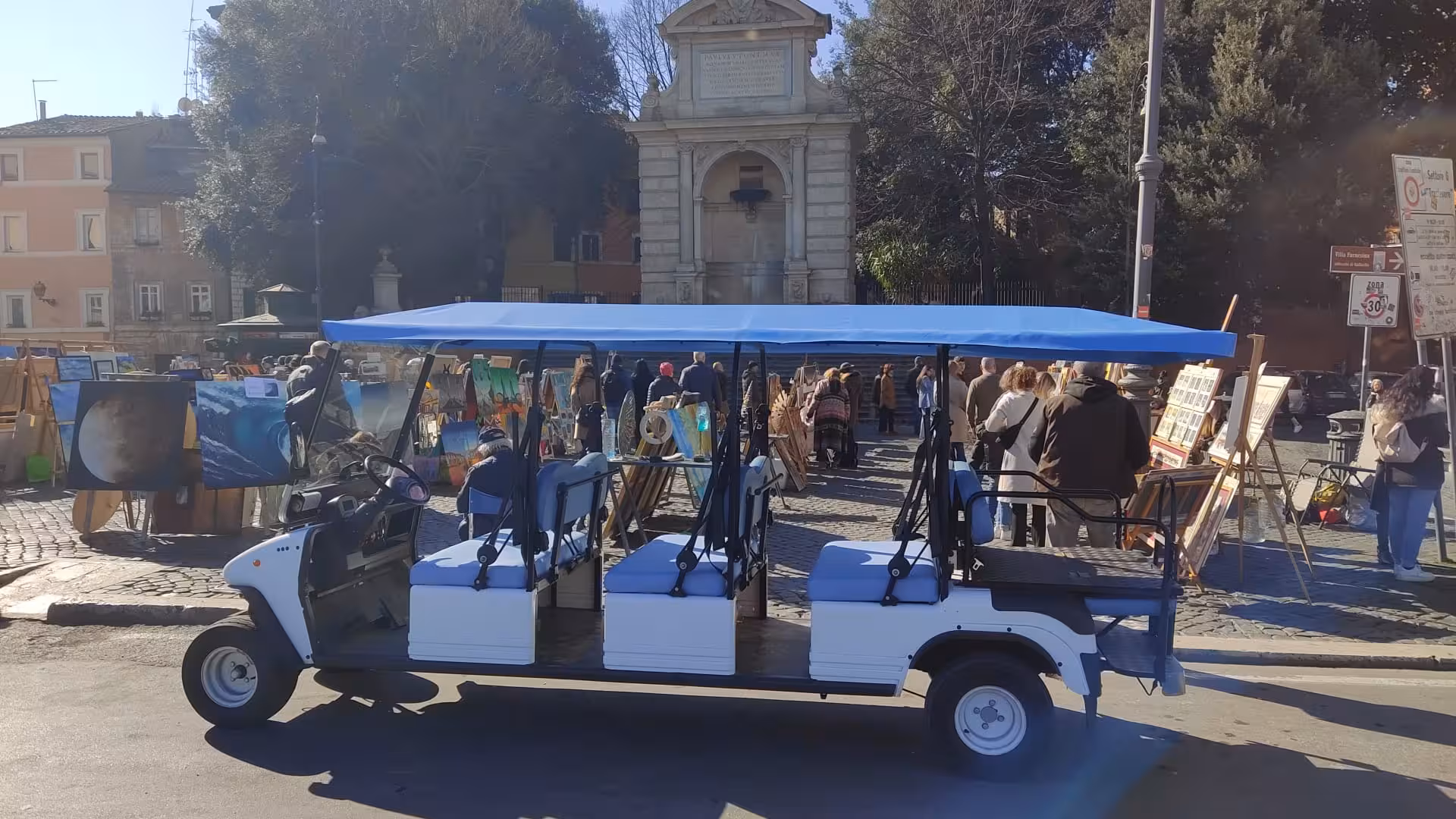 A golf cart awaits passengers at a vibrant art market in Rome, highlighting cultural exploration opportunities.