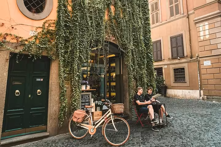Cyclists pause at a charming ivy-covered café in Rome during the golf cart tour with a local guide.