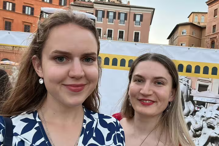 Two women smiling during a self-guided walking tour in Rome with historic buildings in background