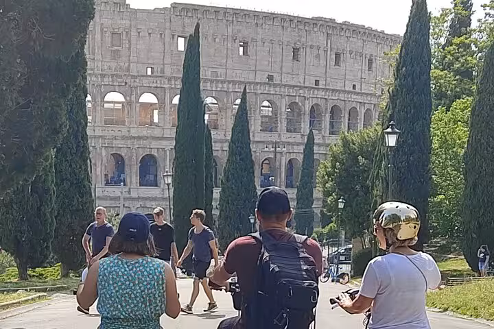 Cyclists enjoying a scenic view of the Colosseum during the Rome Highlights by E-Bicycle small group tour.