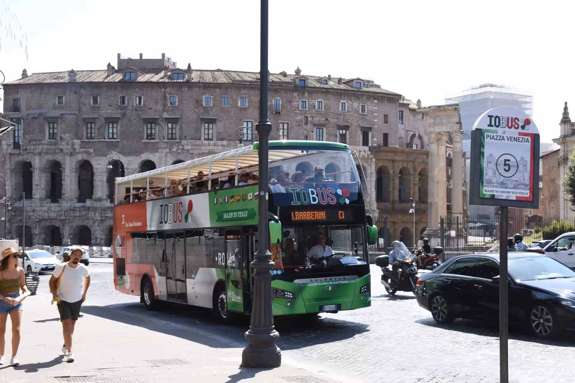 Open-top tour bus near Rome's ancient ruins on a sunny day, ideal for the Sunset in Rome Combo Tour experience.