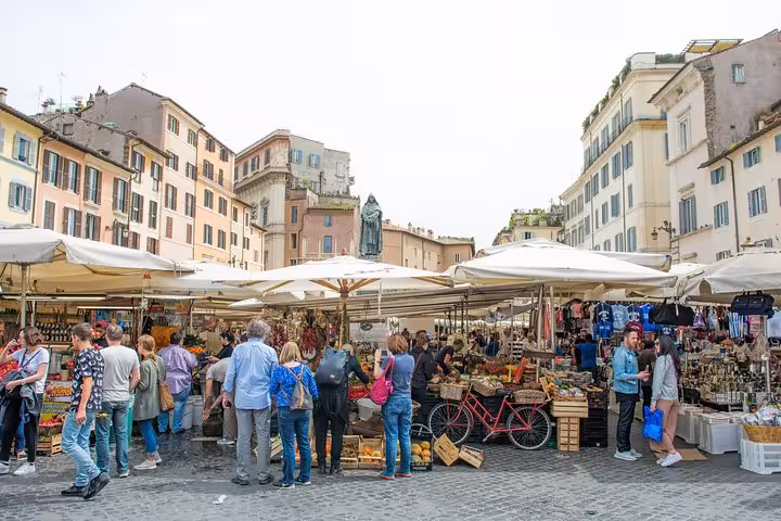 Bustling outdoor market in Rome with visitors exploring stalls under umbrellas, perfect for a walking food tour.