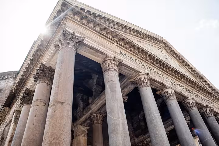 Sunlight illuminates the grand columns and ancient inscriptions of Rome's iconic Pantheon, a marvel of Roman engineering.