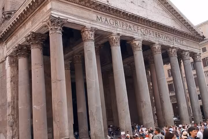 Explore the grand entrance of Rome's Pantheon with towering columns and vibrant crowds, perfect for a historic audio-guided tour.
