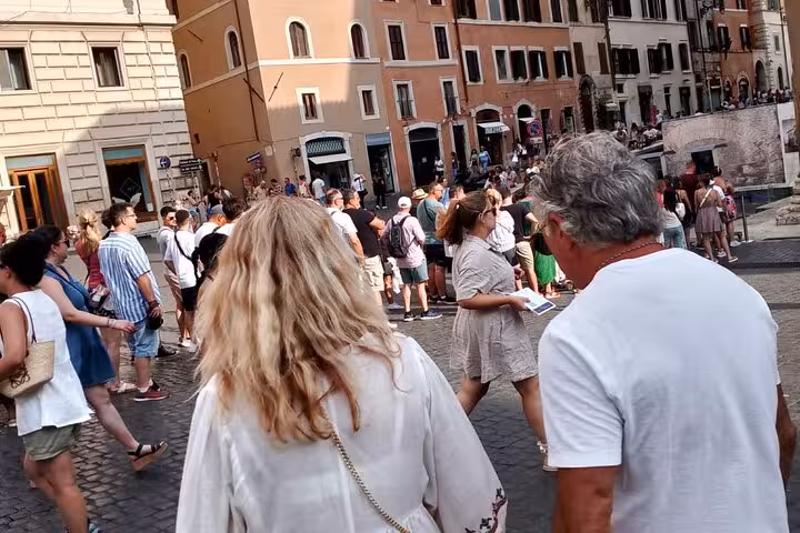 Tourists stroll through a bustling square near Rome's Pantheon, surrounded by charming historic buildings.
