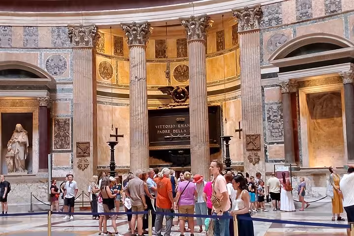 Tourists explore the interior of Rome's Pantheon, surrounded by ancient columns and detailed art, with audio guides in hand.