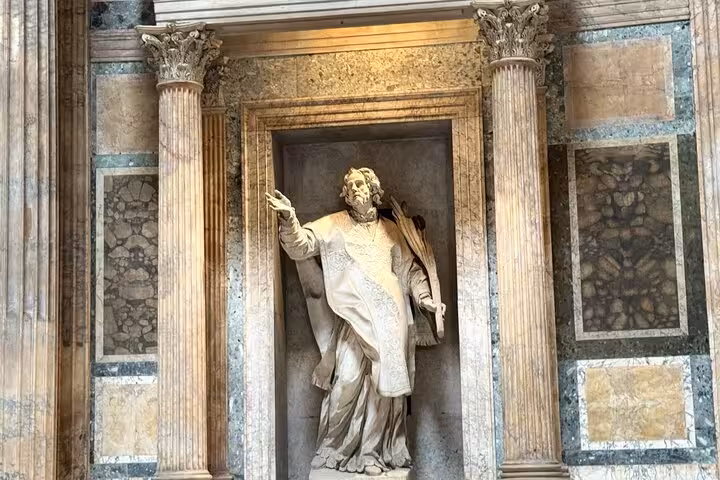 Intricate marble statue nestled between ornate columns inside the historic Pantheon in Rome, Italy.