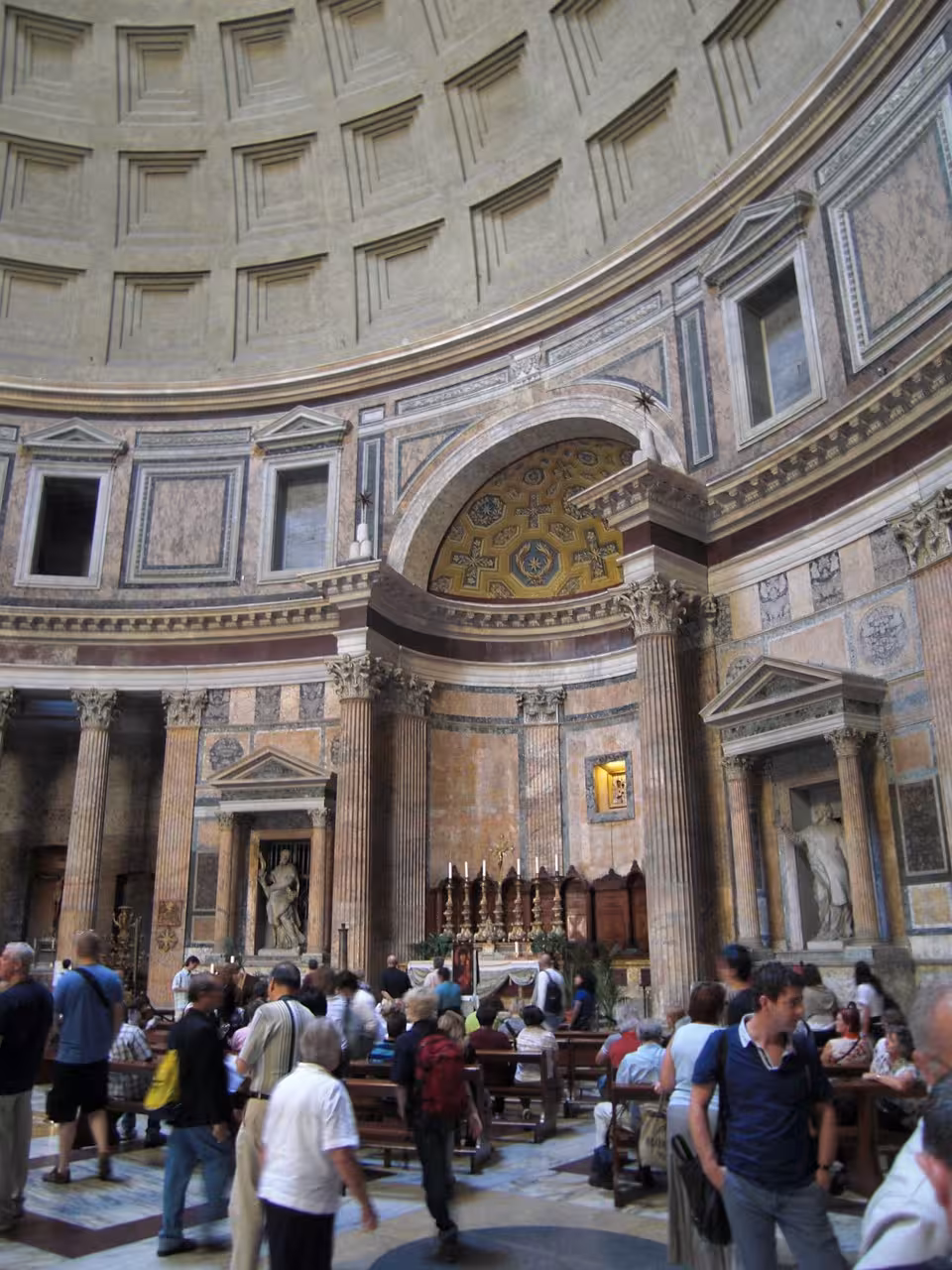 Tourists exploring the Pantheon's ornate interior, featuring stunning arches and historical sculptures in Rome.