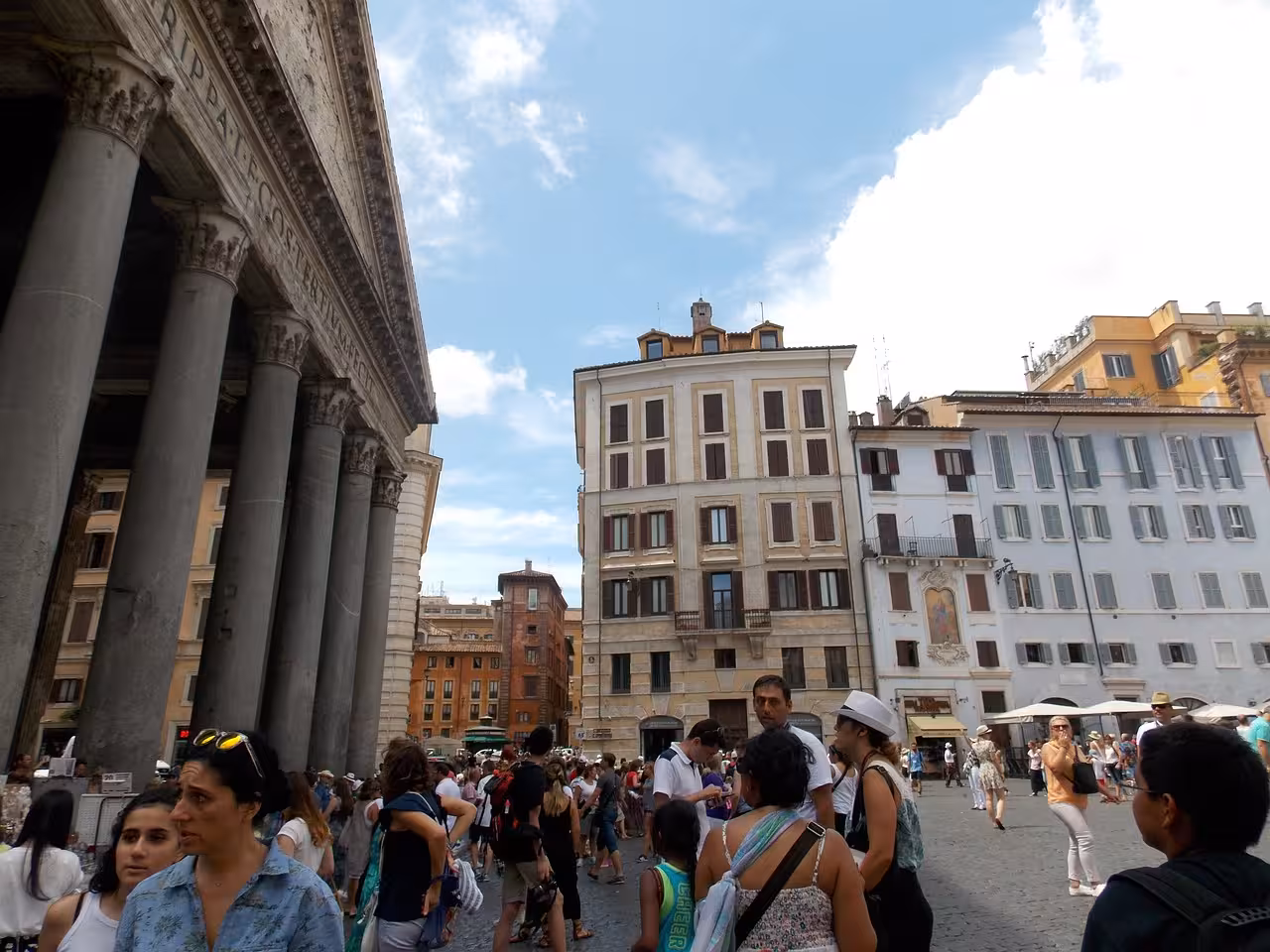 Visitors explore the bustling Piazza della Rotonda, adjacent to the majestic columns of Rome's historic Pantheon.