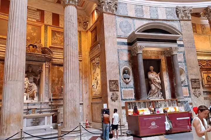 People observe detailed sculptures and rich decorations within Rome's Pantheon, showcasing its architectural splendor.