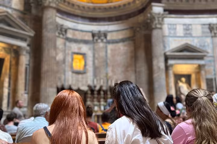 Visitors seated inside the majestic Pantheon, admiring the ancient architecture and domed ceiling.