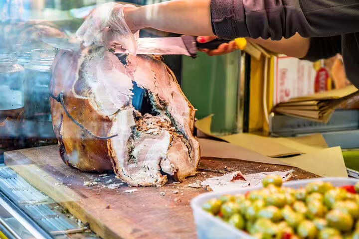 Person slicing savory porchetta with olives nearby during Italian aperitivo tour offering stunning Vatican views.