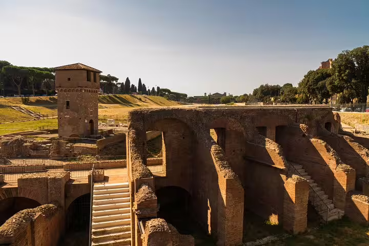 Ancient ruins and historic architecture in Rome under a clear blue sky, featured on a private walking tour of city highlights.
