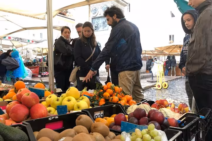 Visitors explore fresh produce at Campo de' Fiori market during the Rome Rione Parione private walking food tour.