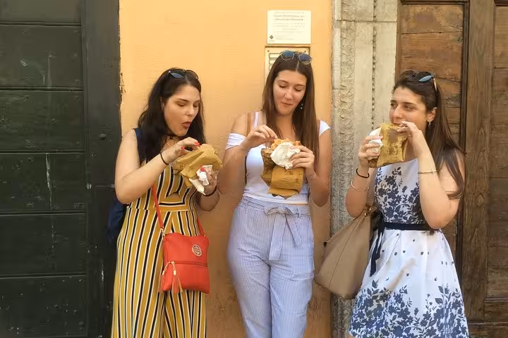 Three women enjoying traditional Roman street food during a private walking tour in Rione Parione, Rome.