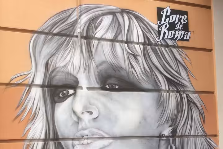Black and white mural of a woman's face with 'Core de Roma' text in Rome's street art scene.