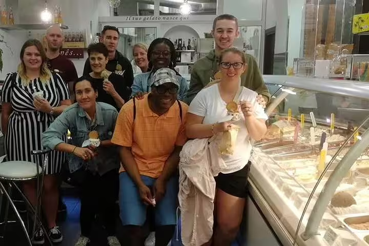 A cheerful group of tourists enjoying authentic Italian gelato at a gelateria during a Rome street food tour near the Pantheon.
