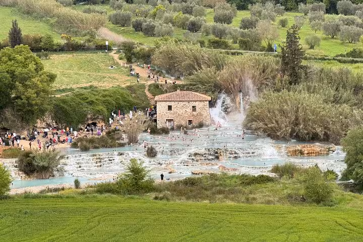 Scenic view of Terme di Saturnia's cascading thermal pools surrounded by lush greenery, ideal for a private Rome getaway.