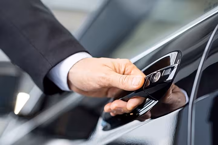 Professional chauffeur opening a car door, symbolizing premium private transfer service in Rome.