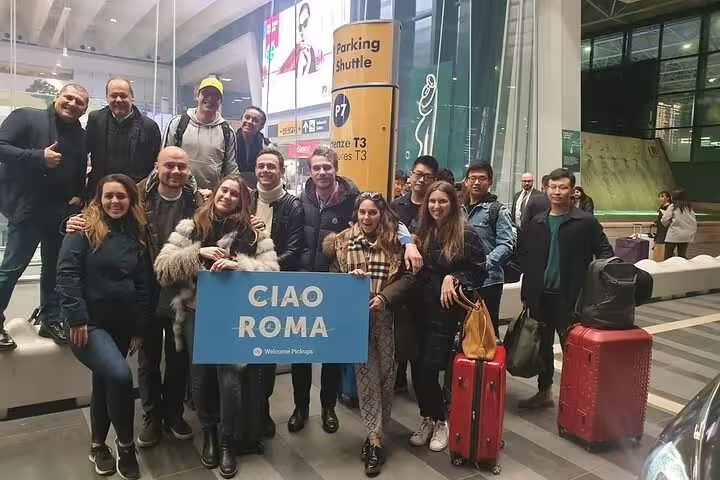 Group of travelers holding a 'Ciao Roma' sign at an airport, ready for a day trip to Tivoli from Rome.