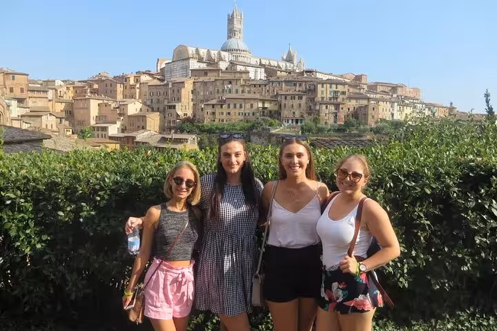 Group of friends posing with Siena's stunning skyline, showcasing a memorable day trip from Rome to Tuscany.