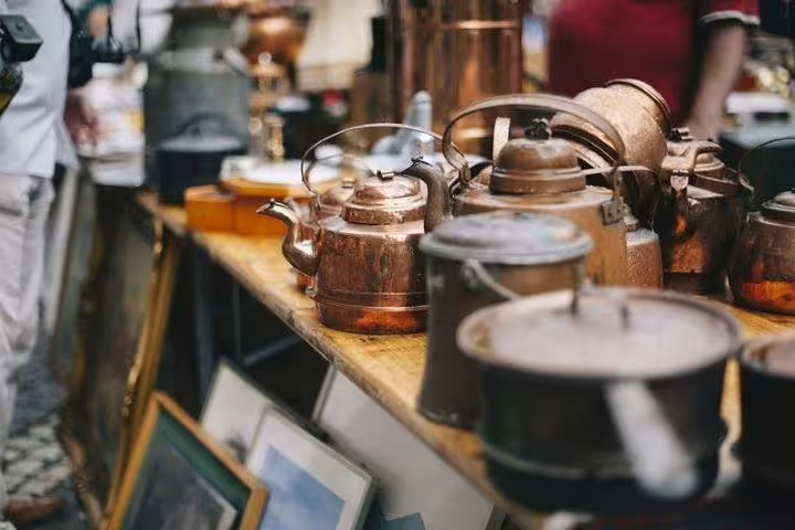 Vintage copper kettles and cookware on display at a Roman street market during a guided half-day shopping tour