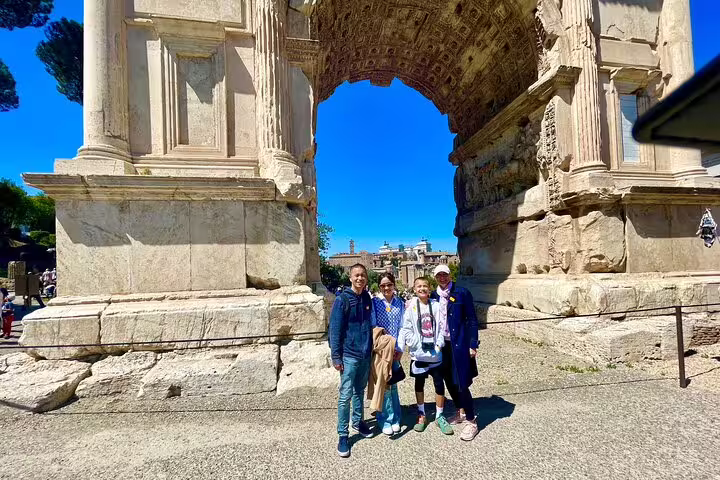 Family enjoying a Rome private VIP tour posing under ancient Arch of Constantine near Colosseum on a sunny day