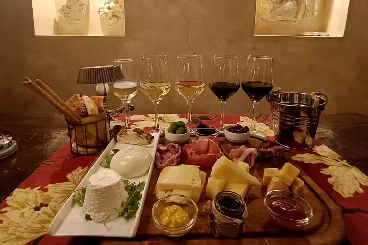 Rome wine tasting experience with assorted cheeses, salumi, olives and sauces paired with red and white wines in a cozy enoteca