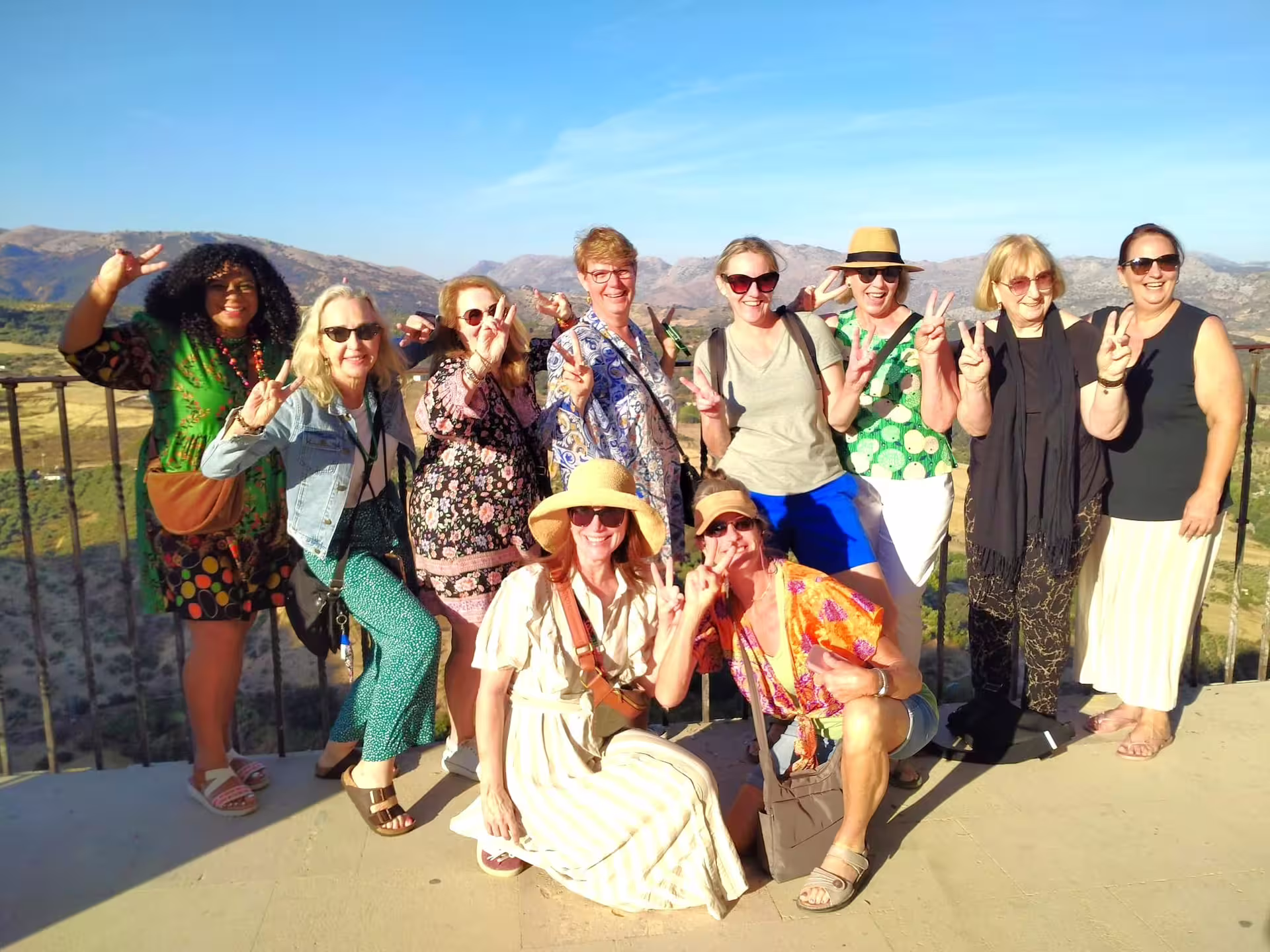 Happy travelers on a Ronda group walking tour posing at a scenic viewpoint with mountains and gorge views