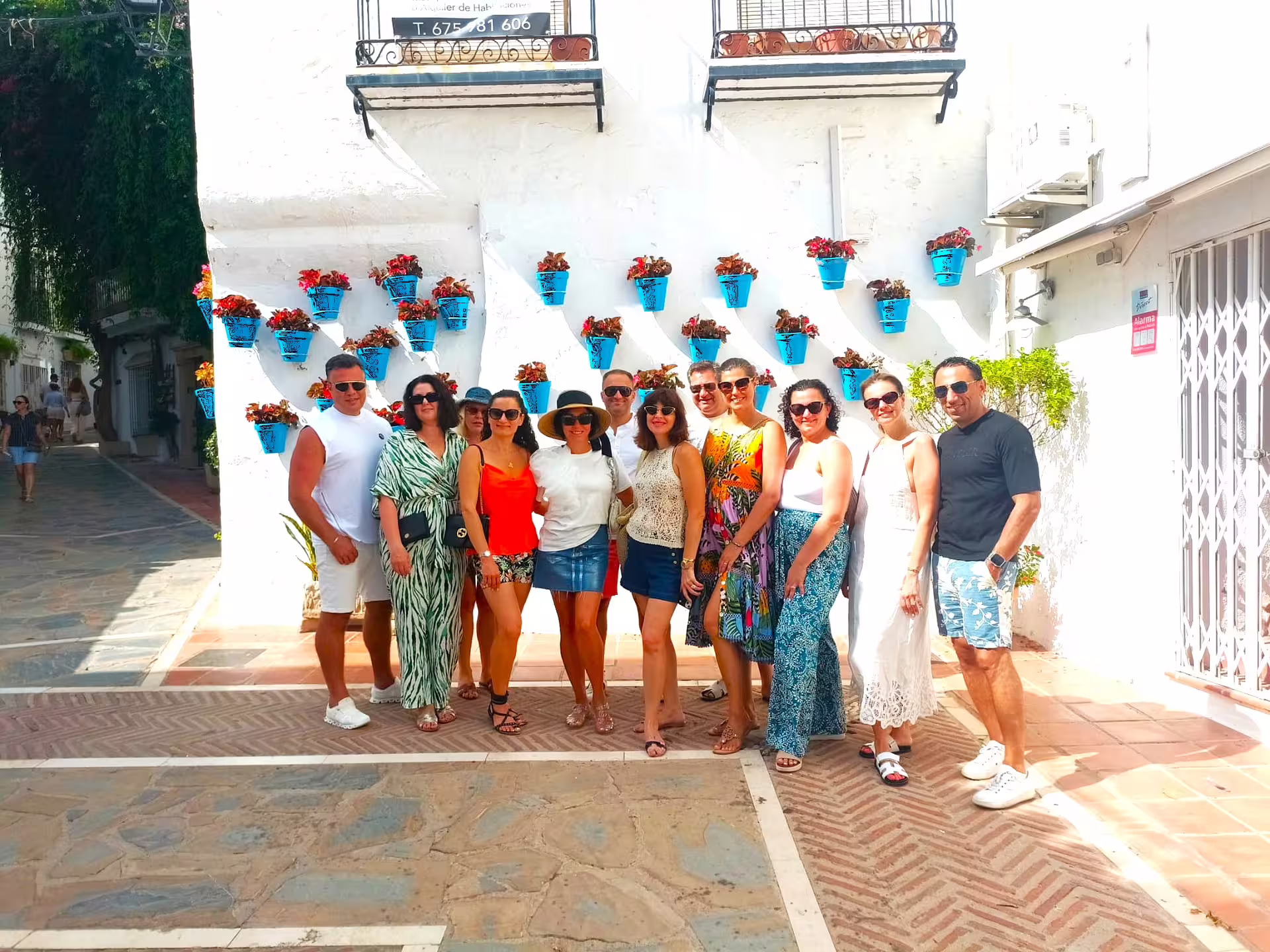 Private Ronda and Marbella day trip guests posing by white wall with blue flower pots, hotel pick-up tour