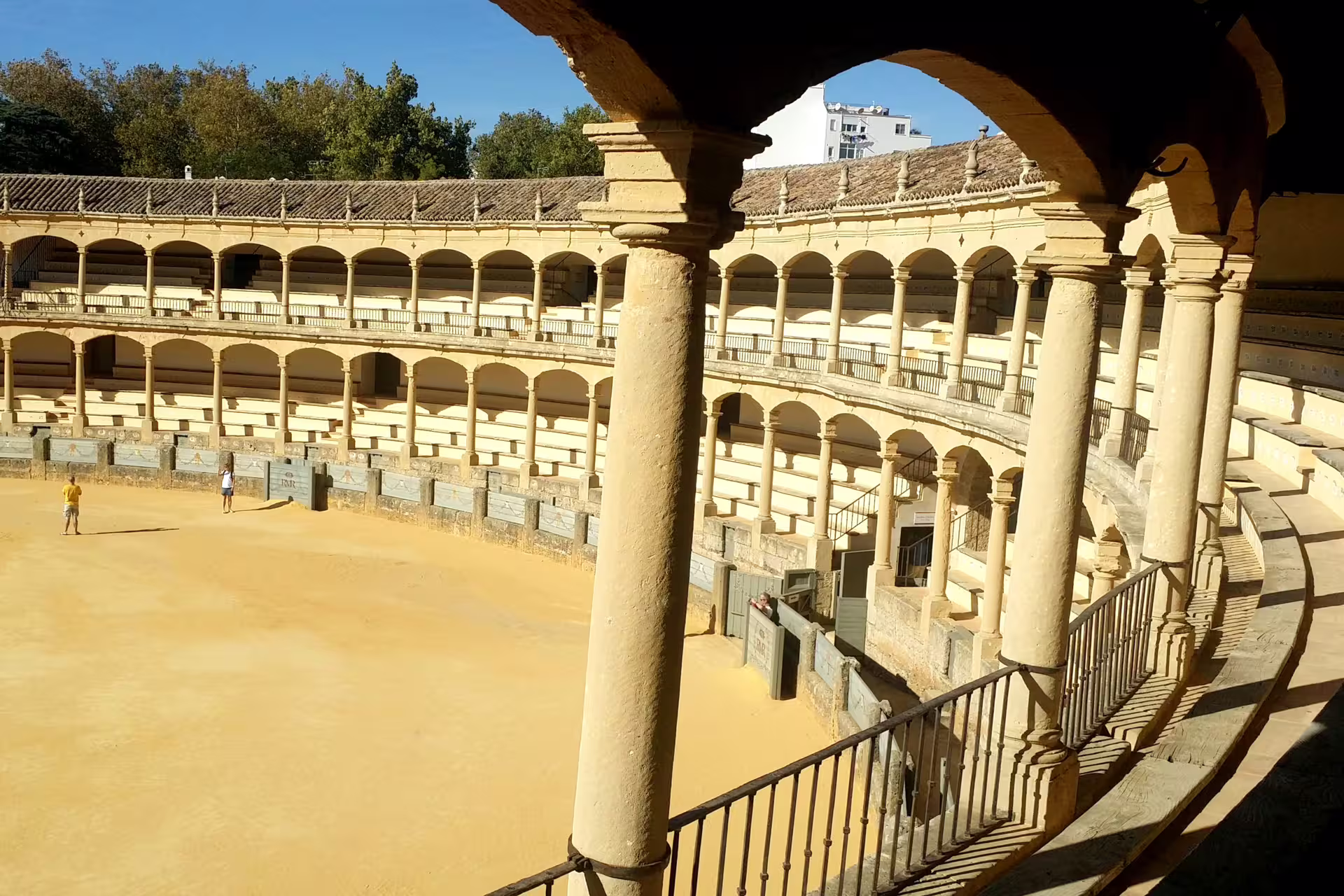 Ronda group walking tour view of Plaza de Toros bullring arches and sandy arena in sunny Andalusia