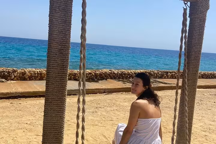 Traveler on a rope swing facing the Red Sea at Ain El Sokhna, relaxing stop on a day tour from Cairo
