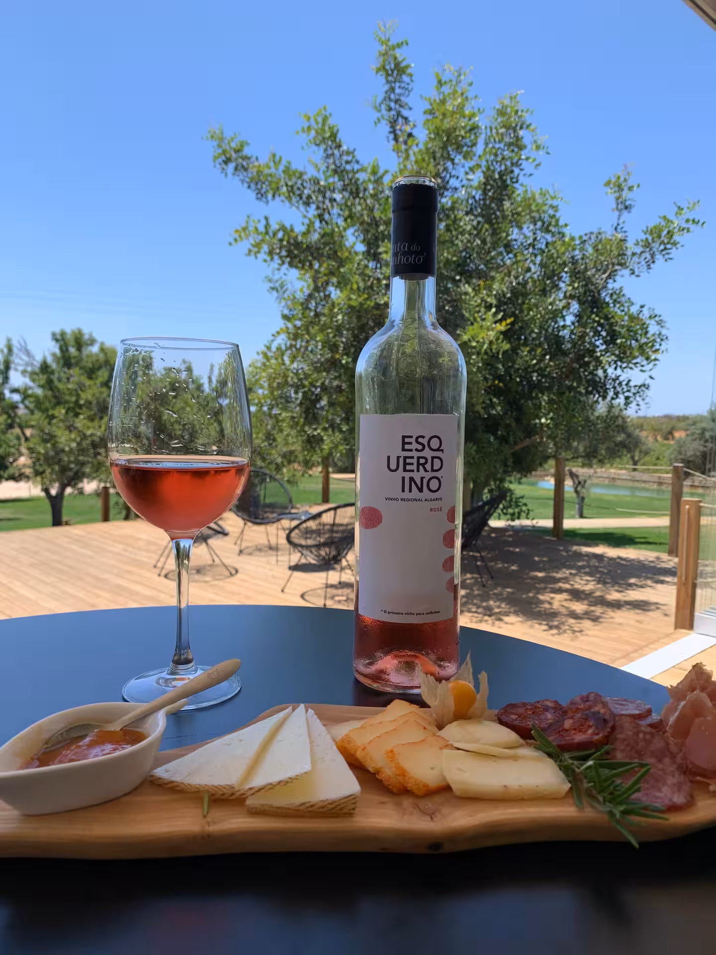 Rosé wine bottle with glass, cured meats and artisan cheeses on outdoor table overlooking Algarve vineyard on half day tour