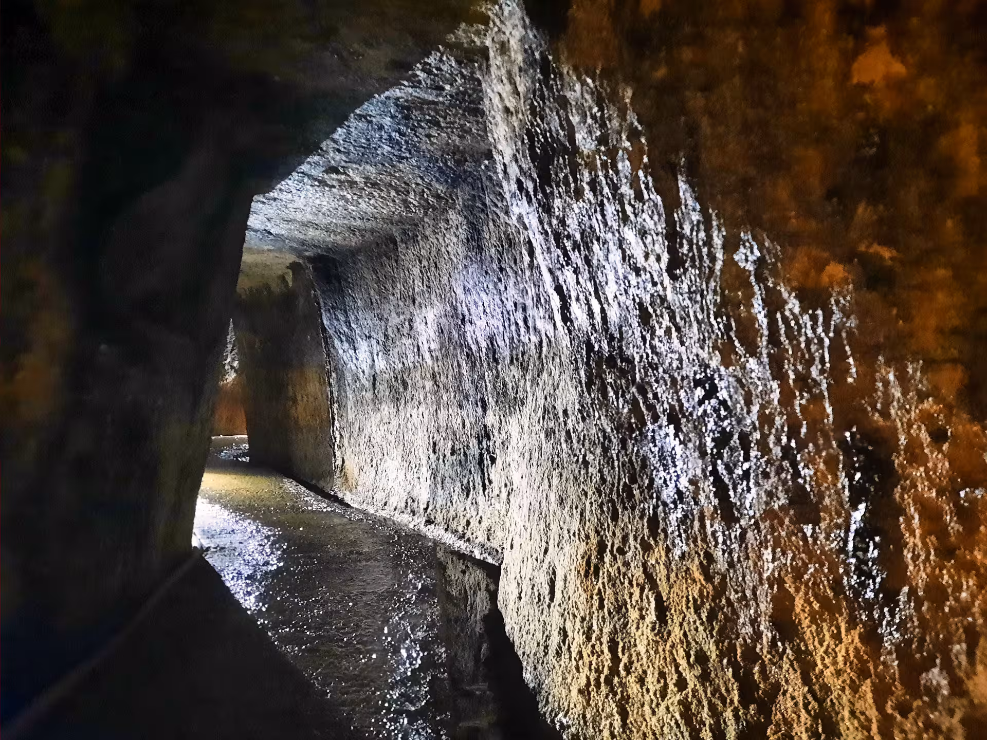 Ancient illuminated rock-cut tunnel with water channel at Rosia Montana Apuseni Mountains