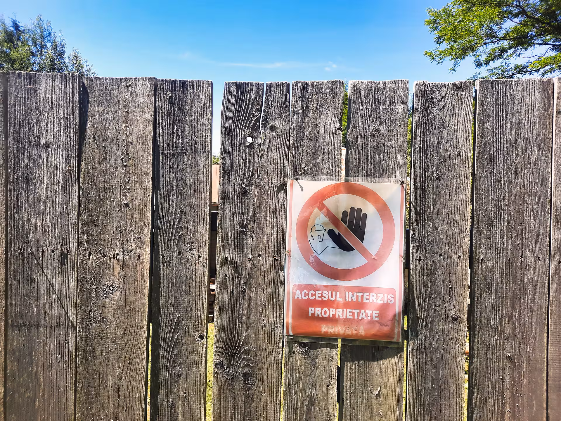 No entry sign in Romanian on weathered wooden fence at Rosia Montana, Apuseni Mountains