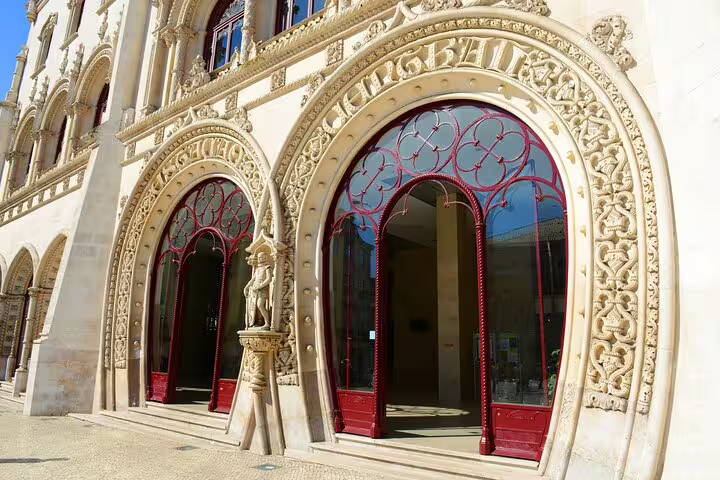 Ornate red and gold arched entrance of Rossio Train Station in Lisbon, showcasing intricate Manueline architecture details.