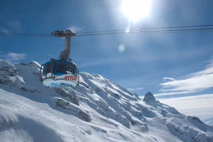 Rotair cable car ascending snowy Mount Titlis peak under bright blue sky in Lucerne, Switzerland