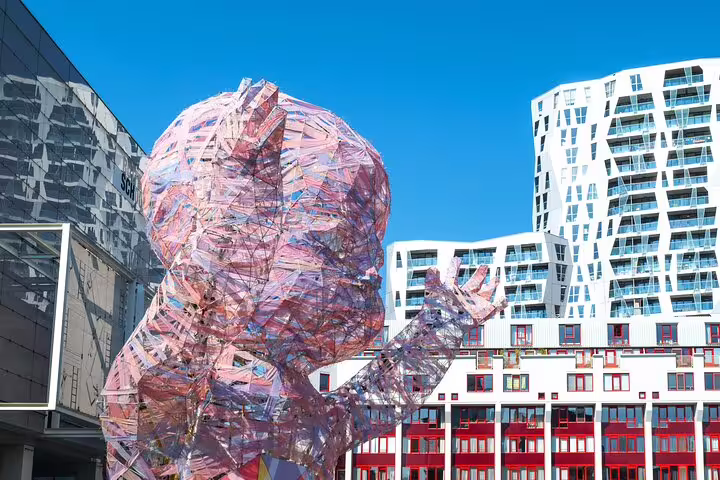 Large reflective human figure sculpture in Rotterdam with modern architecture buildings in background