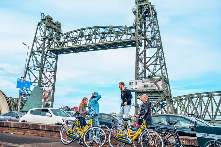 Cyclists pause with yellow bikes at the De Hef bridge on a Rotterdam classic highlights bike tour
