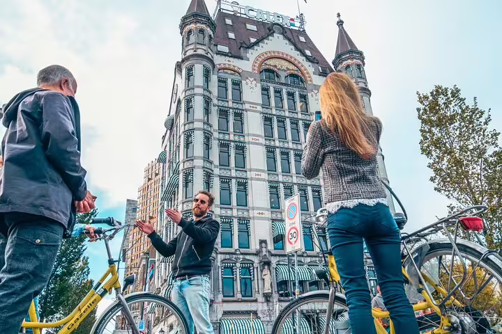 Local guide explains Rotterdam sights by the historic Witte Huis during a classic highlights bike tour
