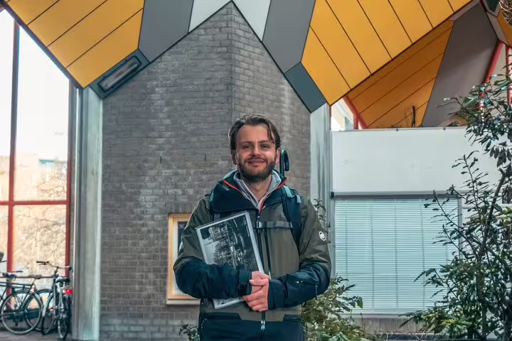 Dutch local guide at Rotterdam Cube Houses holding photos for a highlights and hidden gems walking tour