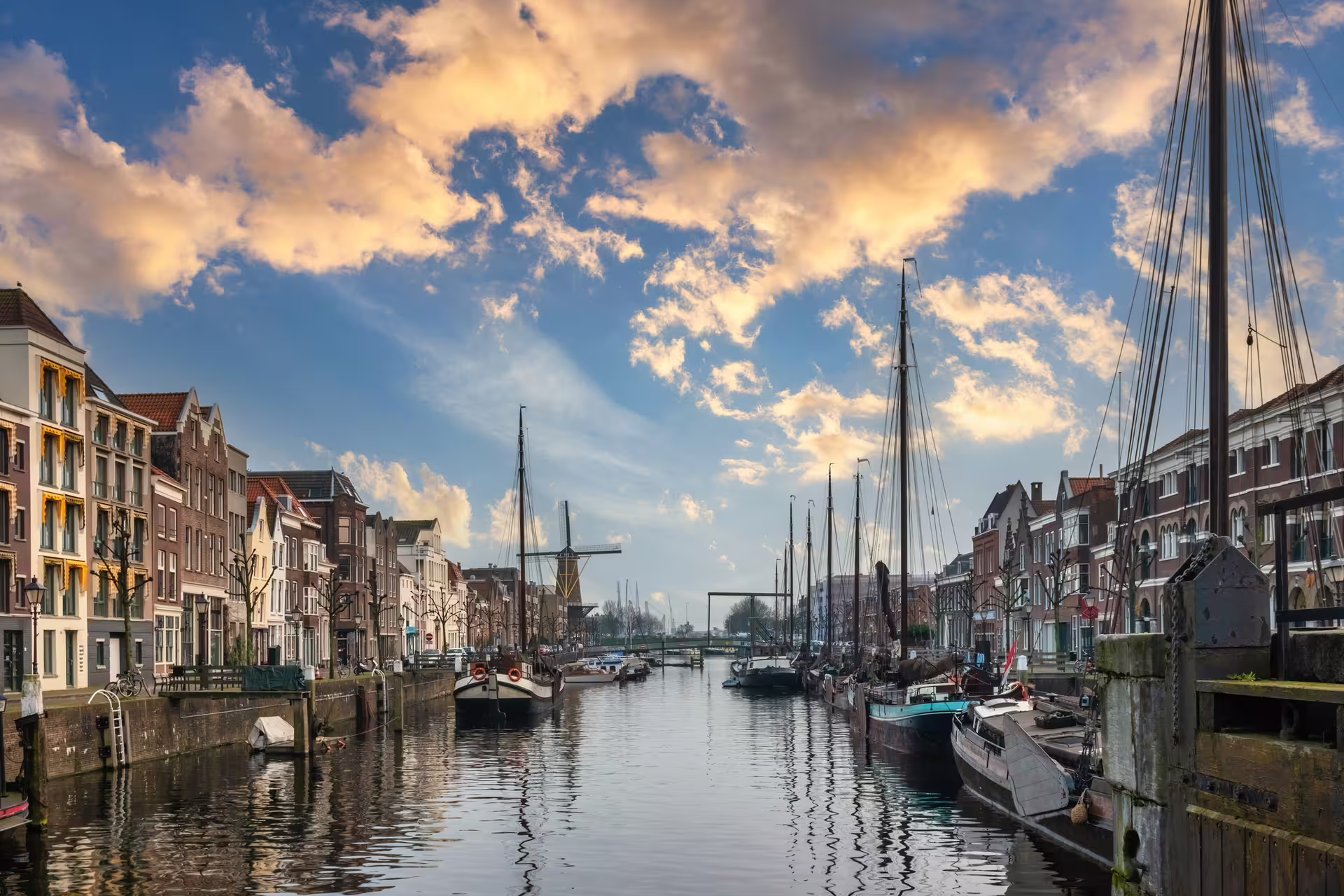 Historic Rotterdam Delfshaven harbor canal with boats at sunset, featured on a 1-day audioguide walking tour