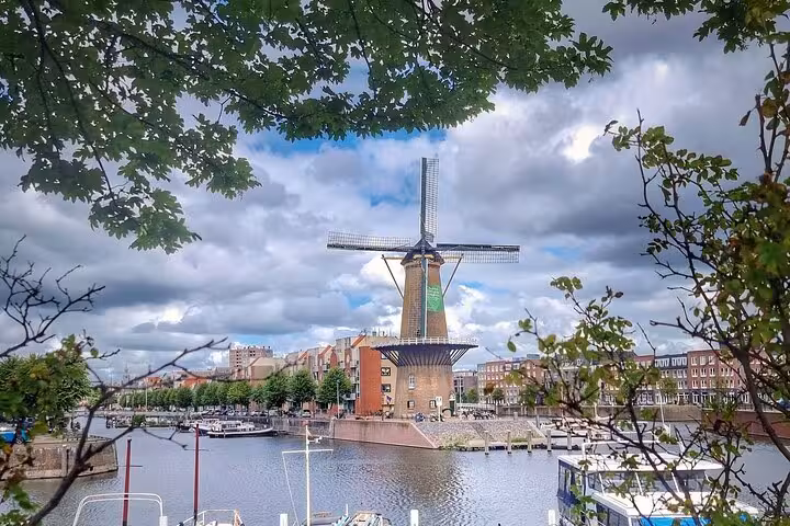 Dutch windmill by the canal in Rotterdam, scenic stop on private tour to historic towns, mills and castle