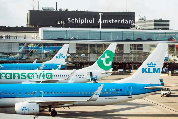 Amsterdam Schiphol Airport terminal with KLM and Transavia planes, private transfer drop-off from Rotterdam