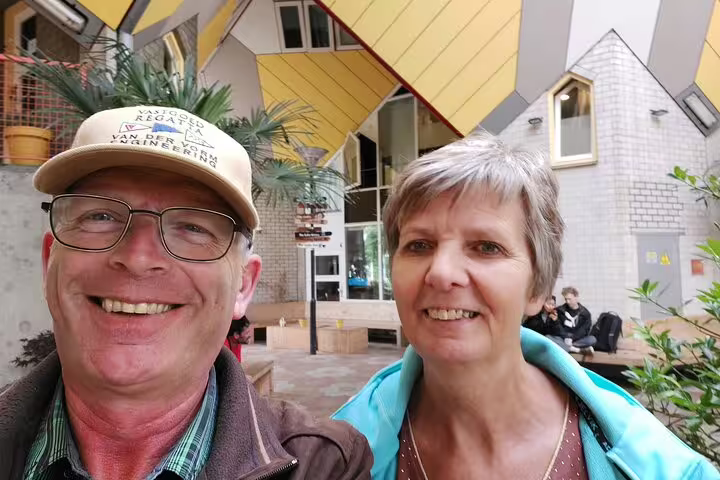 Couple smiling in front of iconic yellow cubic houses in Rotterdam architecture tour