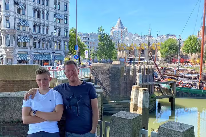 Two visitors posing at Rotterdam's Old Harbour with cubic houses and historic architecture in background
