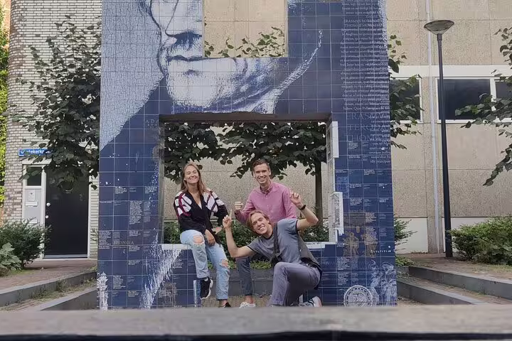 Three friends posing at a blue tile art installation monument during a Rotterdam city walking tour